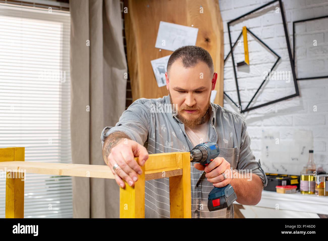 Profesión, carpintería, madera y personas concepto - carpintero con taladro  eléctrico de perforación en un taller de madera Fotografía de stock - Alamy