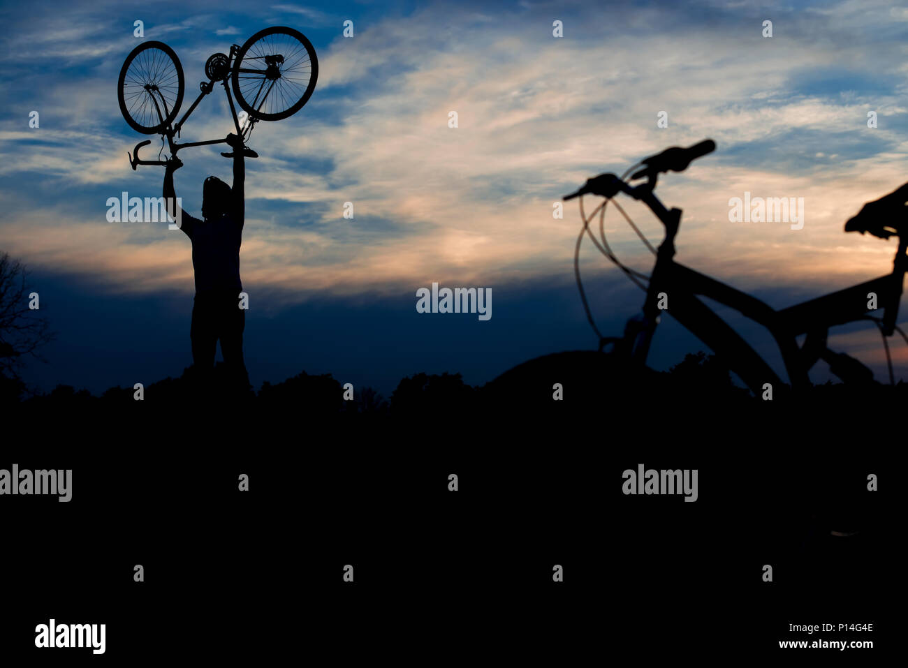 caja de cartón Estación Polvoriento Silueta de hombre levantando su bicicleta en el aire. Jóvenes ciclistas  bicicleta de elevación por encima de la cabeza en el cielo nocturno de  fondo. La energía vital y el modo de