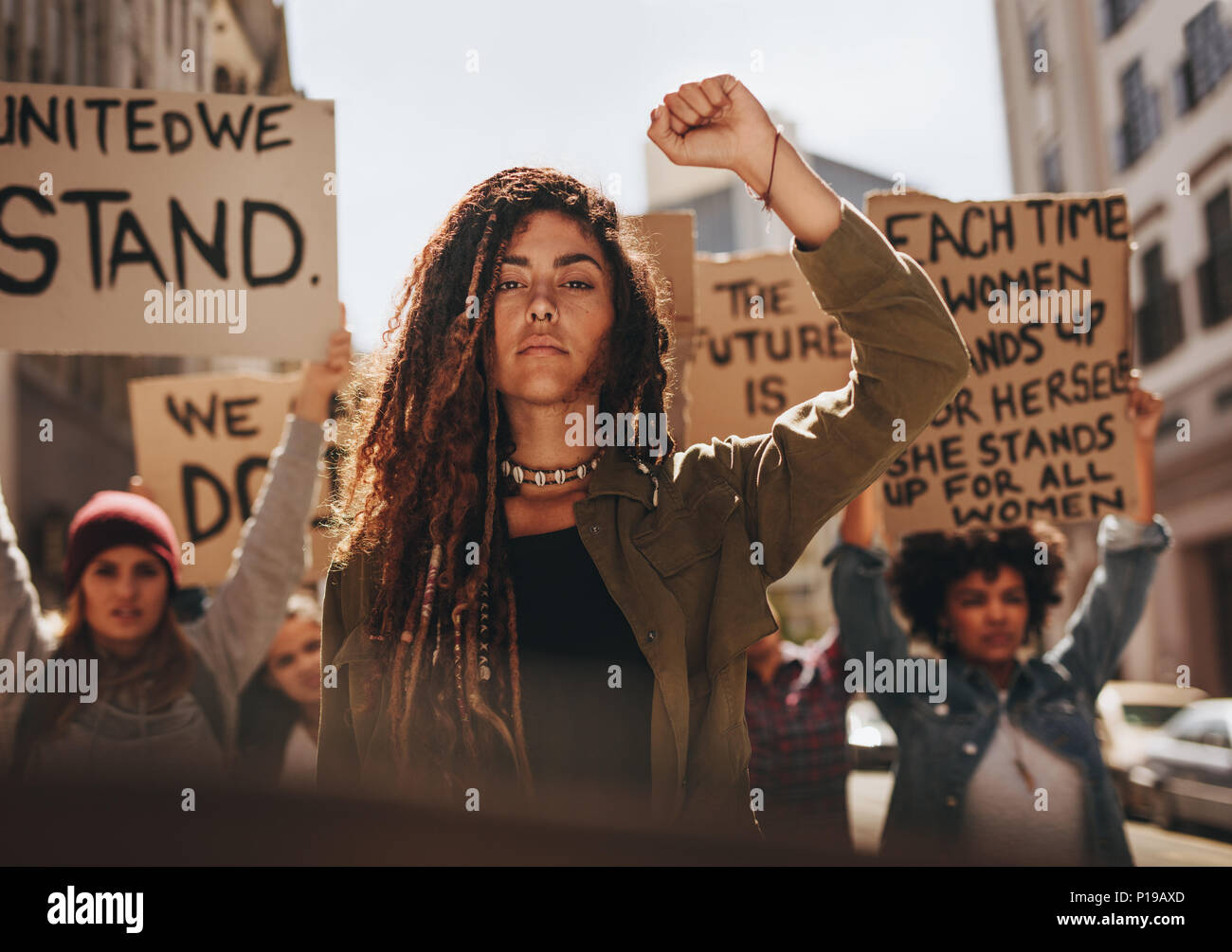 Mujer liderando un grupo de manifestantes en la carretera. Grupo de mujeres protestando por la igualdad y la potenciación de las mujeres. Foto de stock