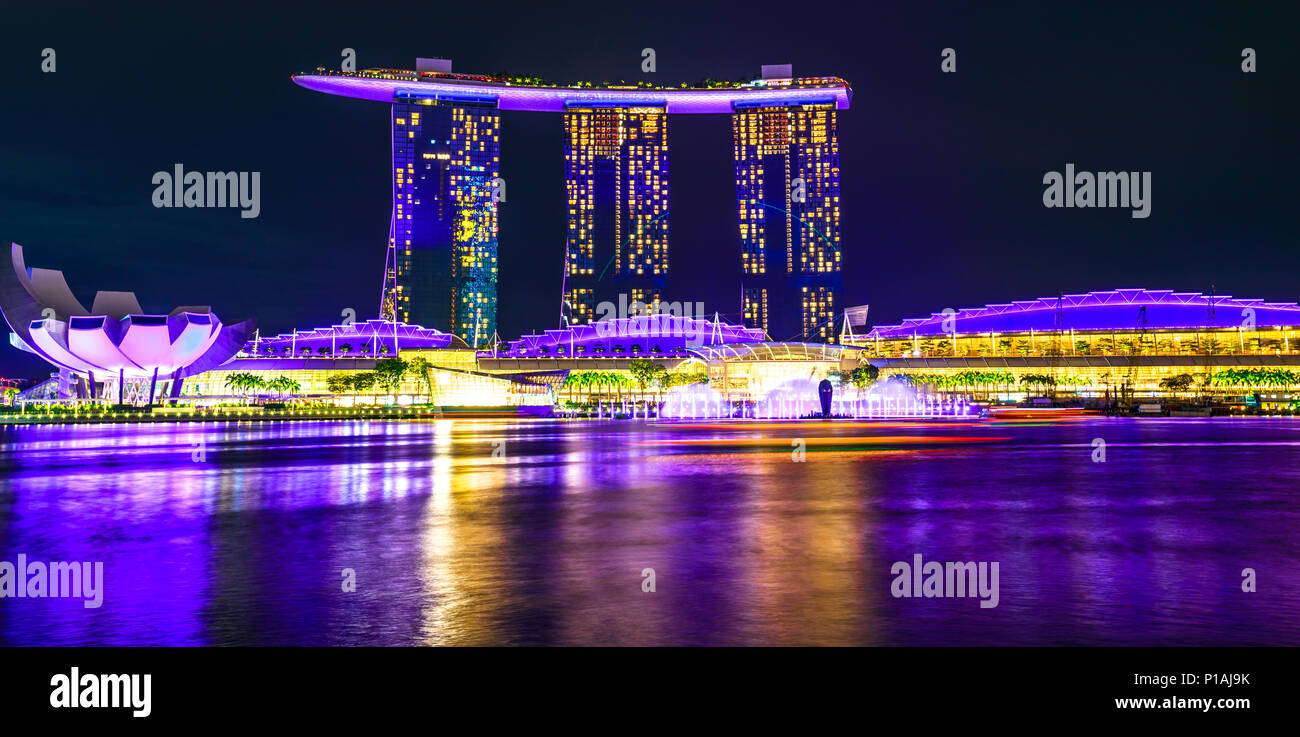 Panorama de la bahía de marina iluminada por la noche. Ciudad de Singapur, en el sudeste de Asia. Escena nocturna waterfront. Larga exposición. Foto de stock