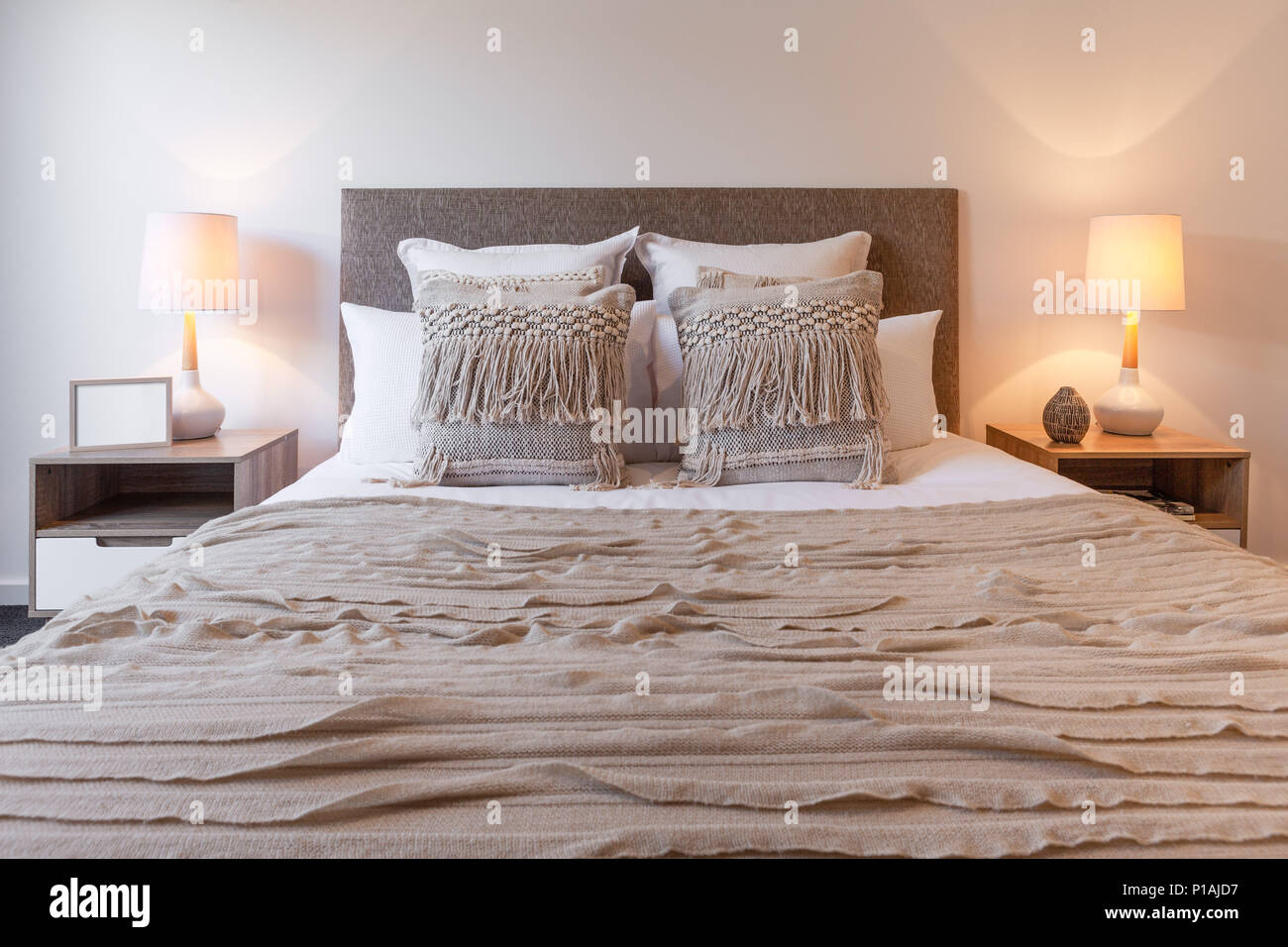 Almohadones decorativos de acuerdo con cama dormitorio lámparas y mesitas de  noche Fotografía de stock - Alamy
