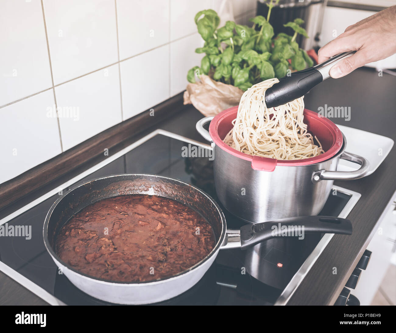 Persona que sirve pasta y salsa boloñesa sobre encimera Foto de stock