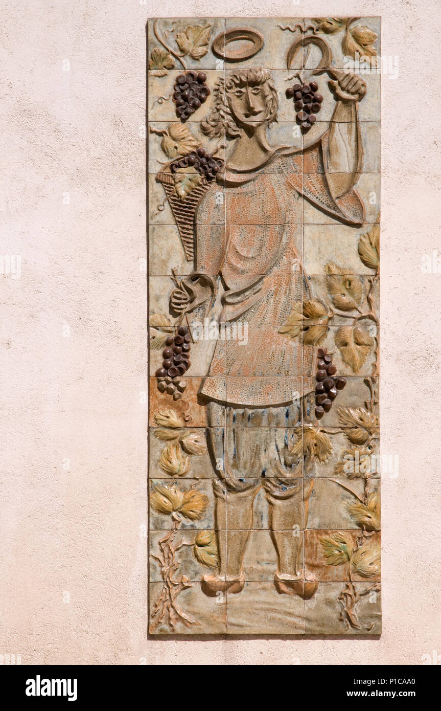 Diseño de socorro en azulejos mostrando el hombre en traje campesino ccollecgting uvas en fachada de Domaine des Vins Place de la Halle, Beaune, Francia Foto de stock