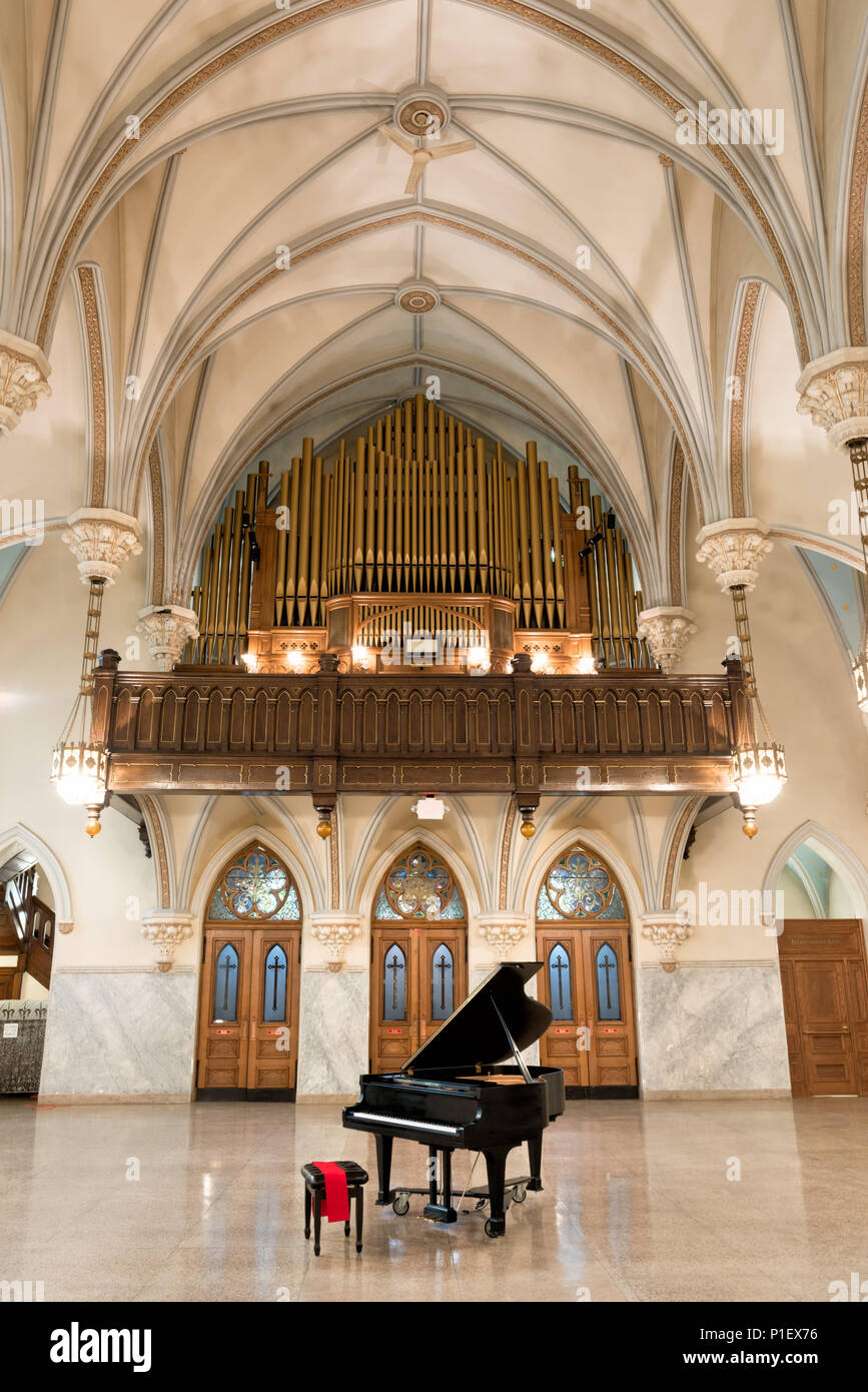 Baby Grand Piano en una gran iglesia abierto y hermoso salón con techos altos con arcos abovedados espectaculares por encima y detrás de órgano de tubos grandes. Foto de stock