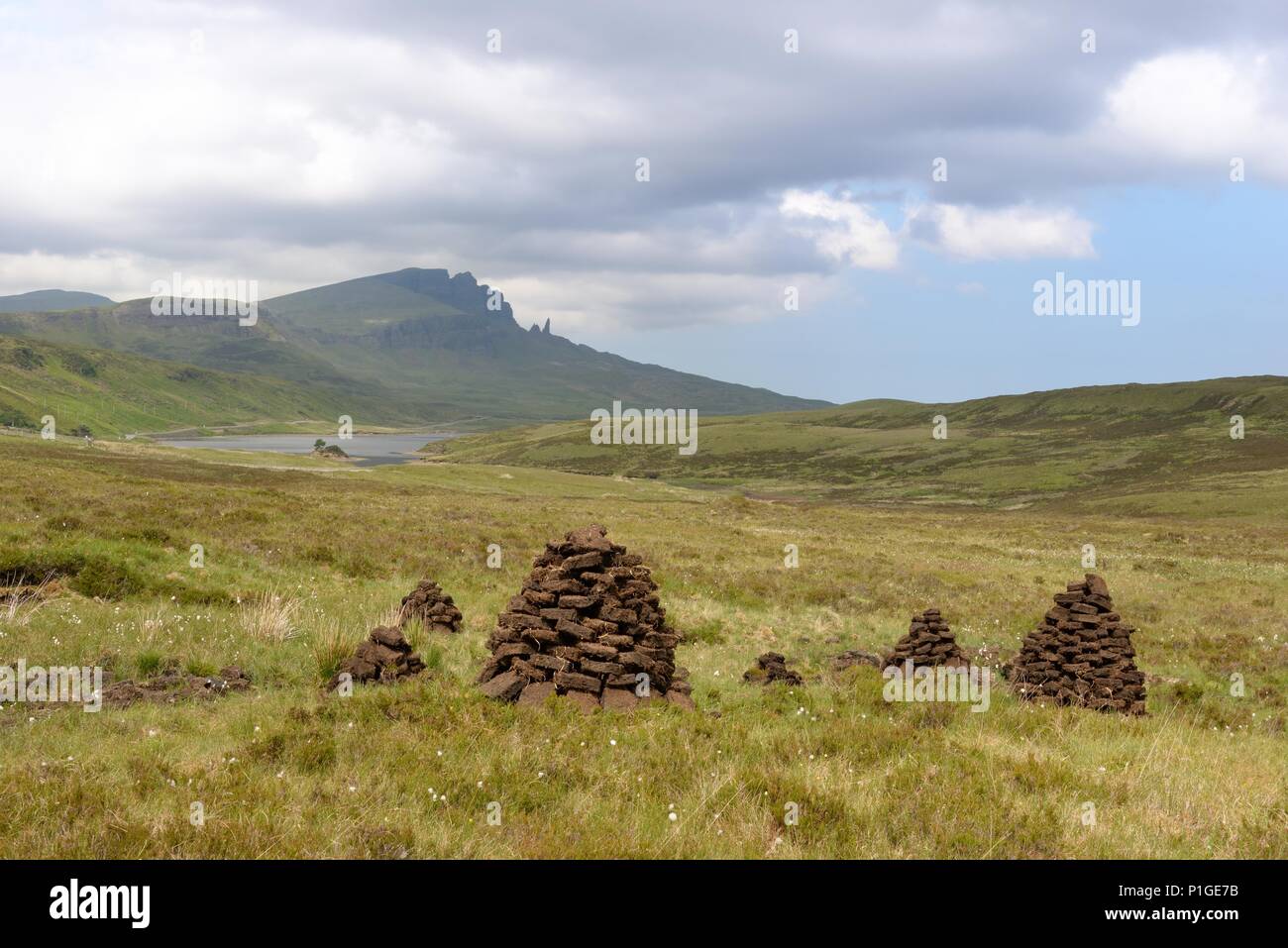 Bloques de cortar turba apilada durante el secado en la península de Trotternish la Isla de Skye, en Escocia. 'El' Storr Rocky Hill proporciona el telón de fondo. Foto de stock