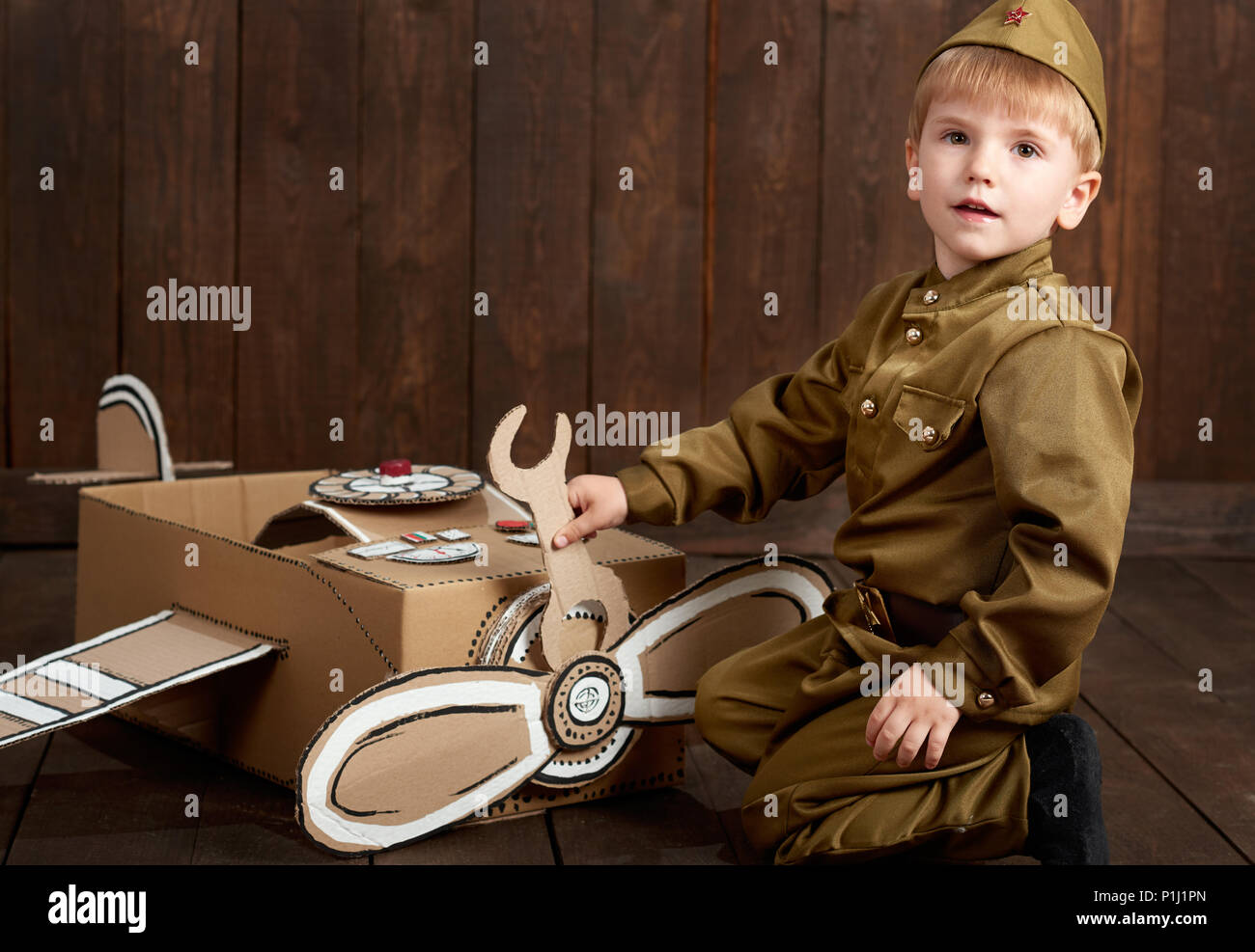 Los niños boy están vestidos como soldado en uniformes militares retro reparar un avión hechas cartón, de madera oscura de estilo retro Fotografía de stock - Alamy