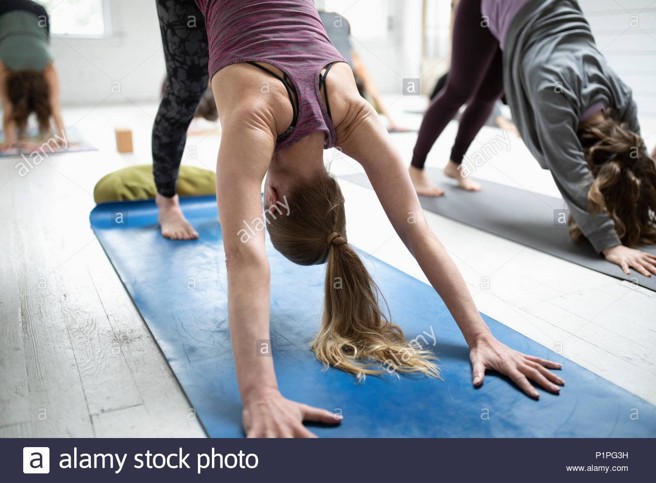 Las mujeres que practican yoga perro boca abajo plantean en clase de yoga Foto de stock