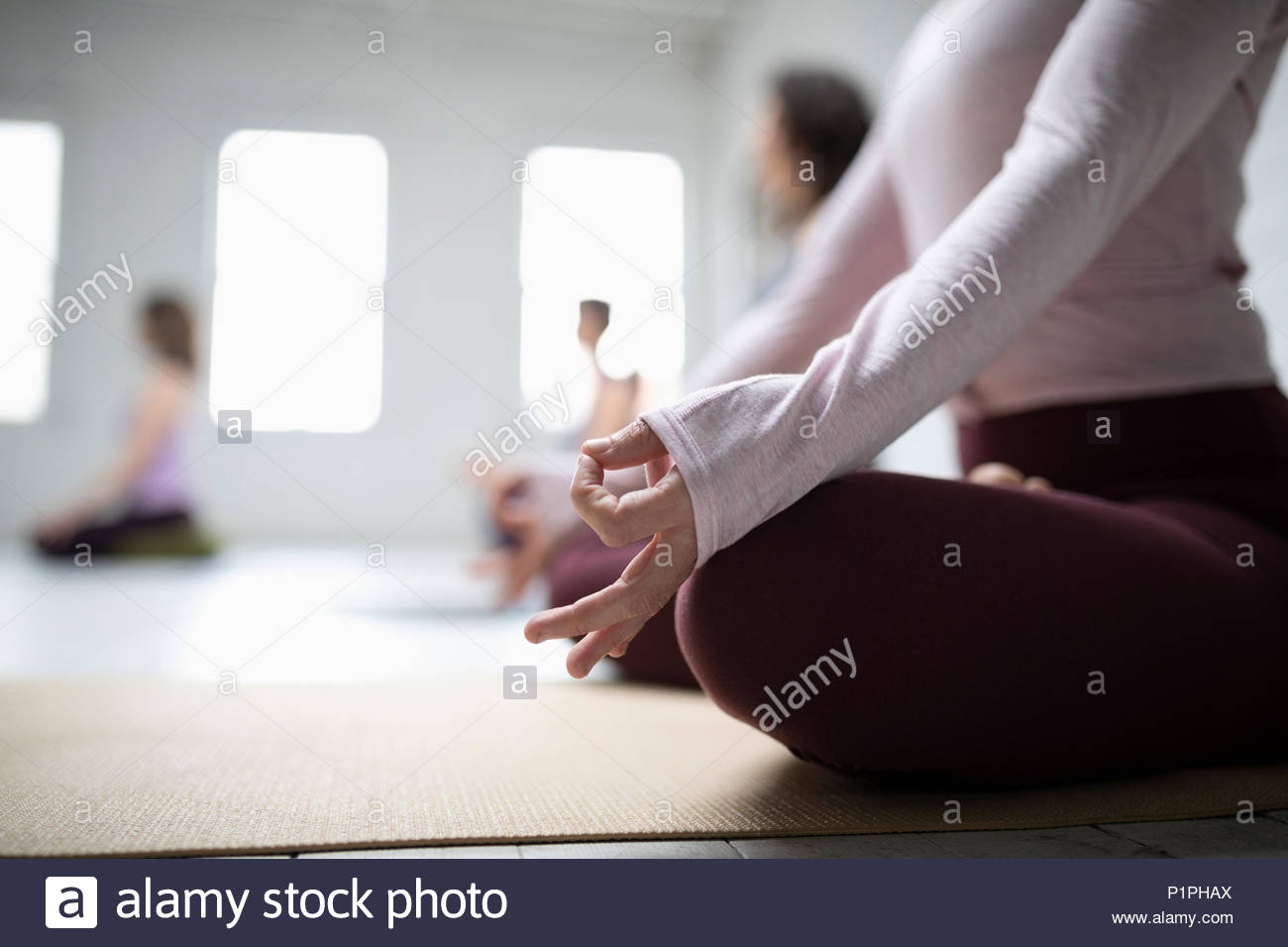 Cerrar mujer practicando la meditación la postura del loto con las manos en gyan mudra en clase de yoga Foto de stock