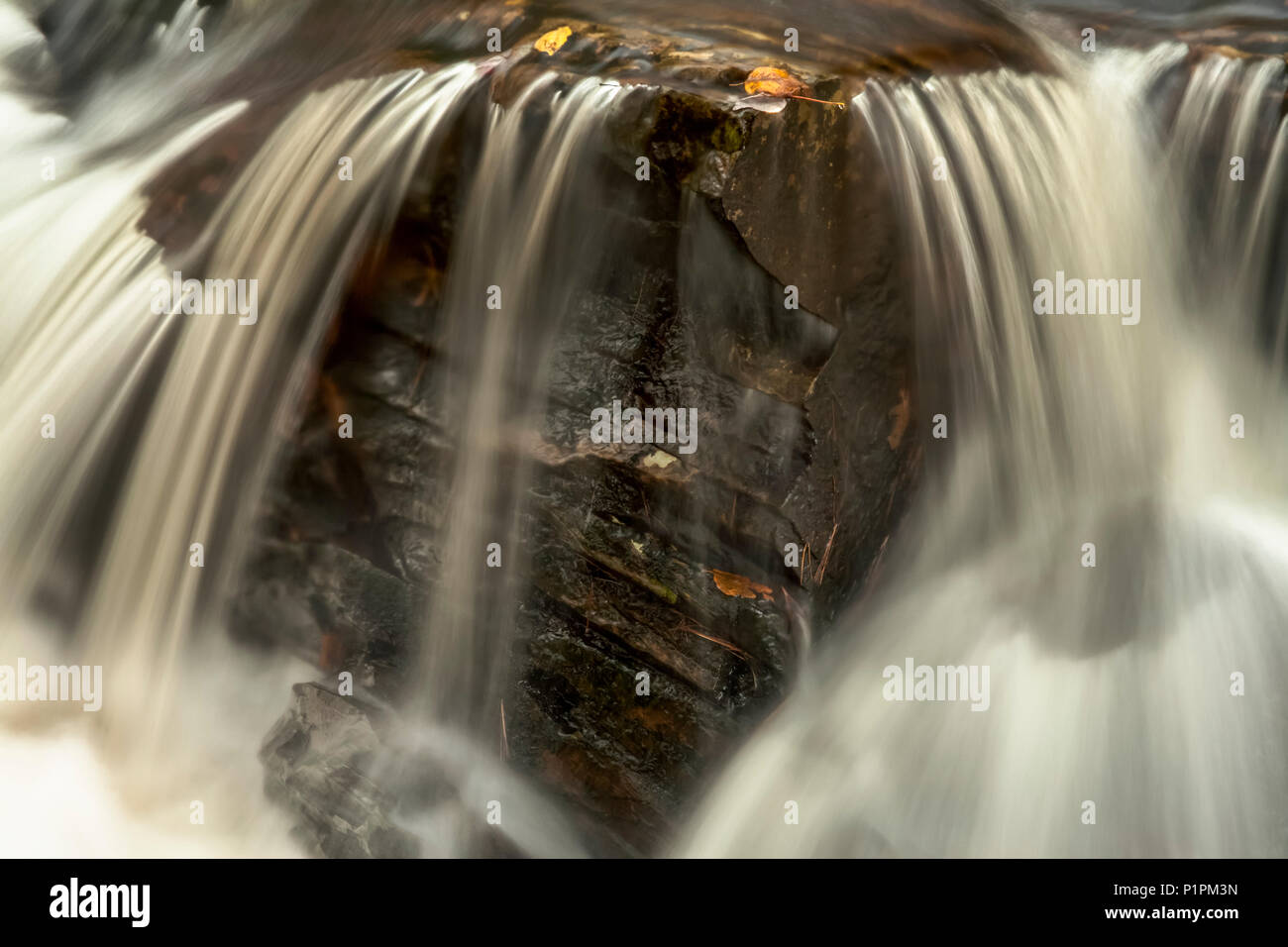 Desenfoque de movimiento del agua que fluye sobre las rocas en Kings Brook, cerca de Ensenada, Sleepy Shubenacadie Grand Lake, Nova Scotia, Canadá Foto de stock