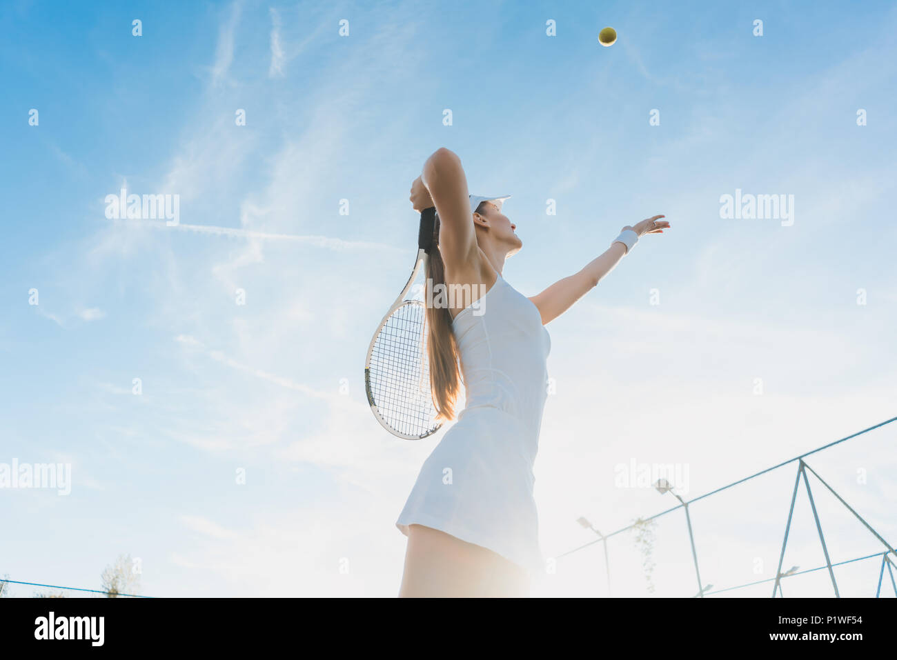 Mujer sirviendo la pelota para jugar un partido de tenis en la cancha Foto de stock
