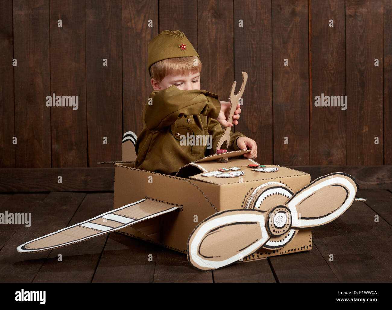 Los niños boy están vestidos como soldado en uniformes militares retro  reparar un avión hechas de cartón, de madera oscura de estilo retro de  fondo Fotografía de stock - Alamy