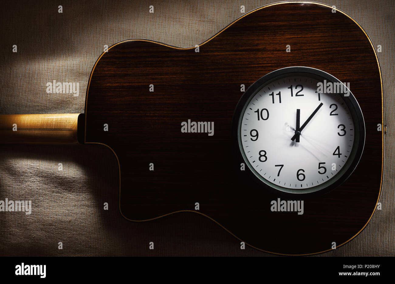 Composición simple, reloj de pared negro sobre una manta de cama mostrando  las doce de la noche y parte de un antiguo retro estilo gitano, guitarra  acústica Fotografía de stock - Alamy