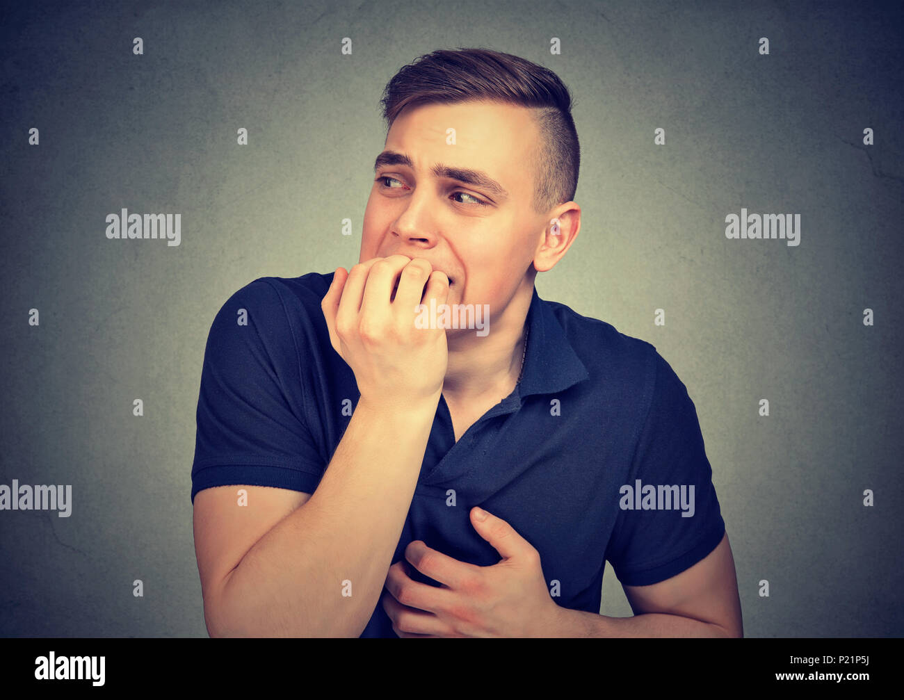 Hombre vacilante ansioso mordiendo las uñas de los dedos de las manos Foto de stock