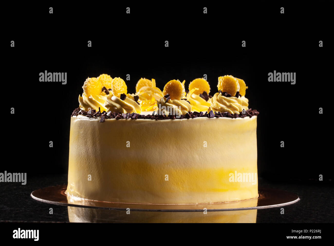 Redondo de color amarillo pastel de cumpleaños. Crema de decoración  decoración de la torta. Fondo negro Fotografía de stock - Alamy