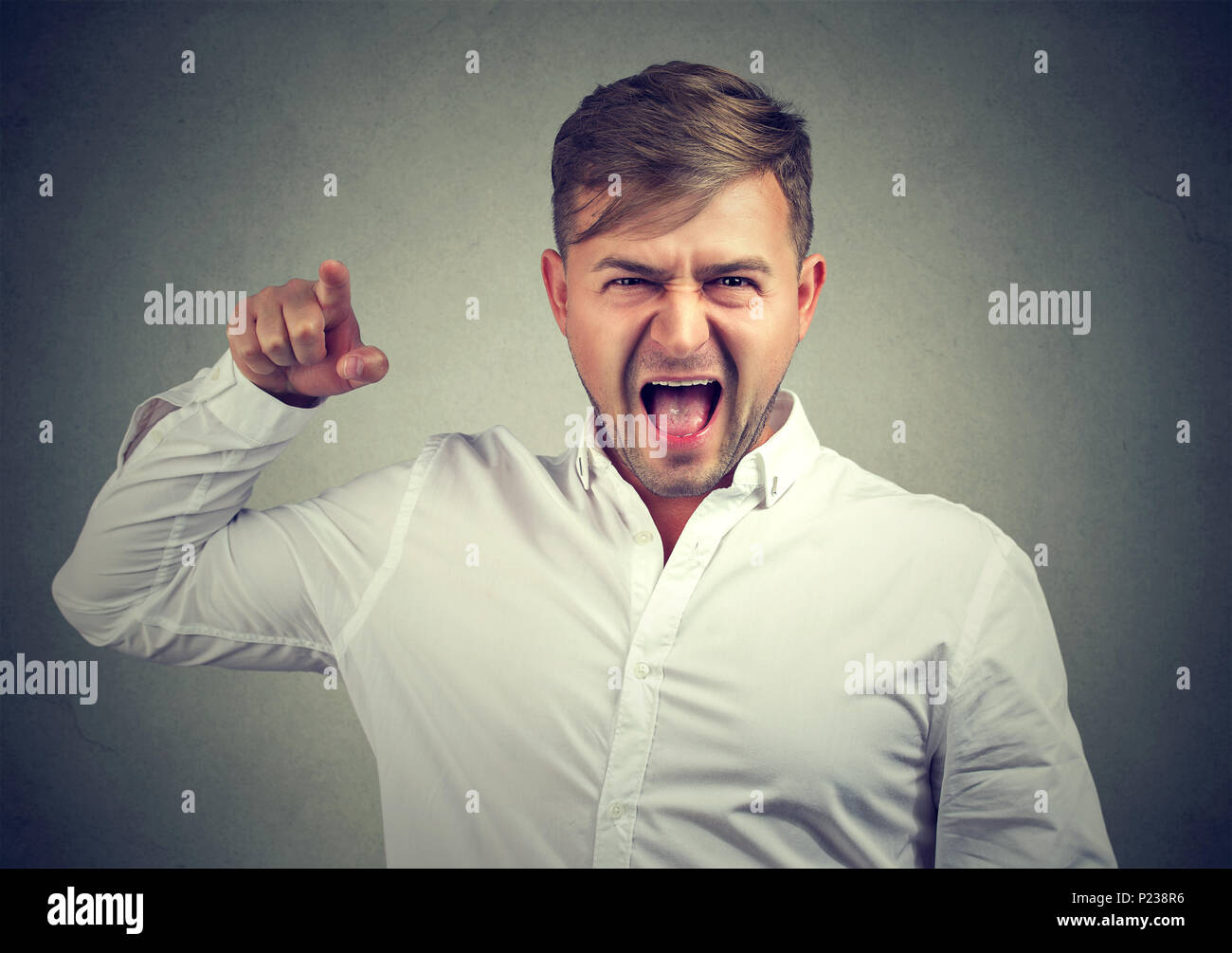 Nervioso hombre gritando con la camisa blanca apuntando con el dedo a la cámara tengan conflicto y acusando en fallo. Foto de stock