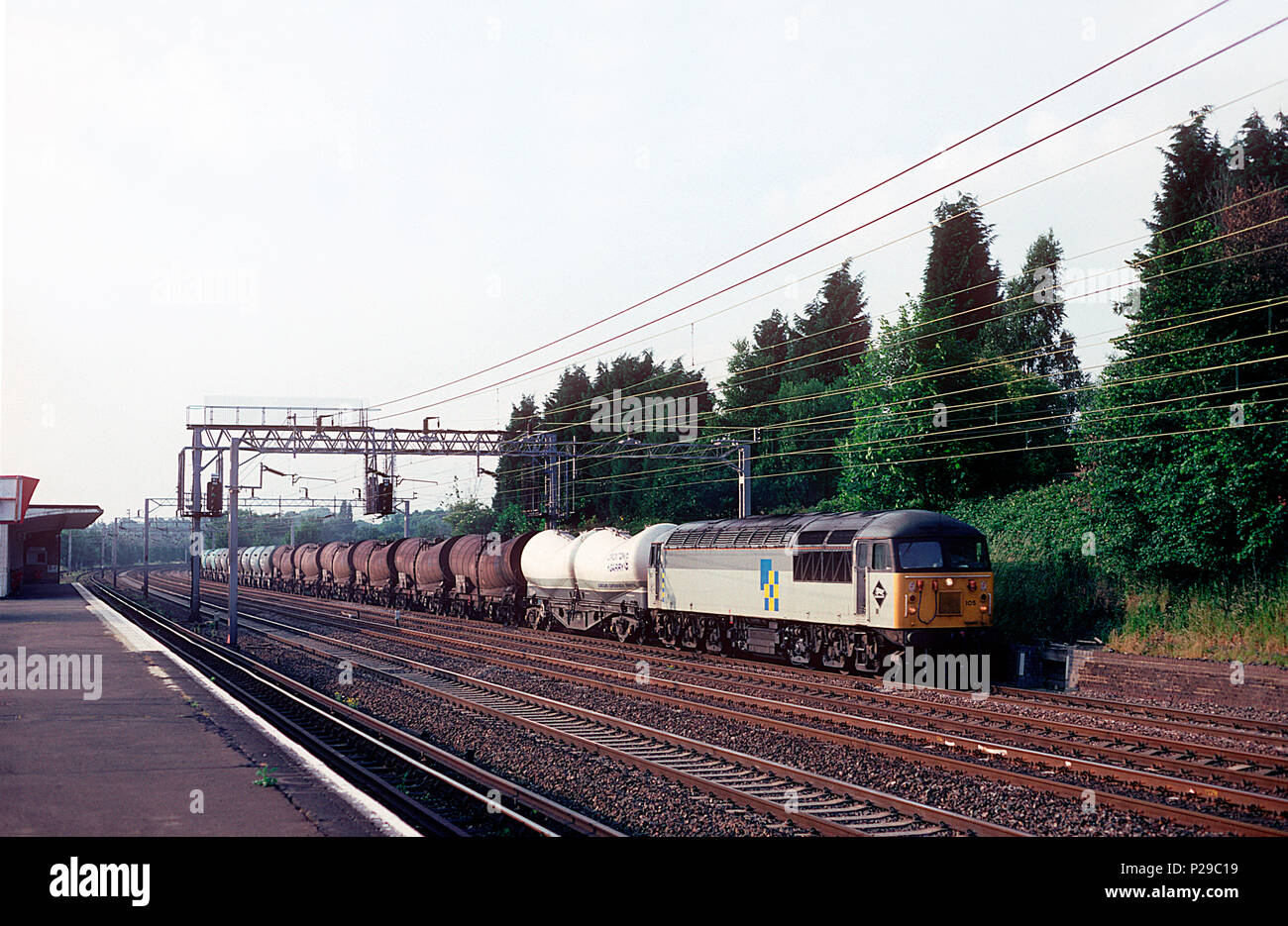 Una clase 56 locomotora diesel número 56105 se dirige hacia el sur a lo largo de la línea principal de la Costa Oeste con un tren de mercancías compuesto por una variedad de vagones cisterna en Carpenders Park. El 25 de junio de 1994. Foto de stock