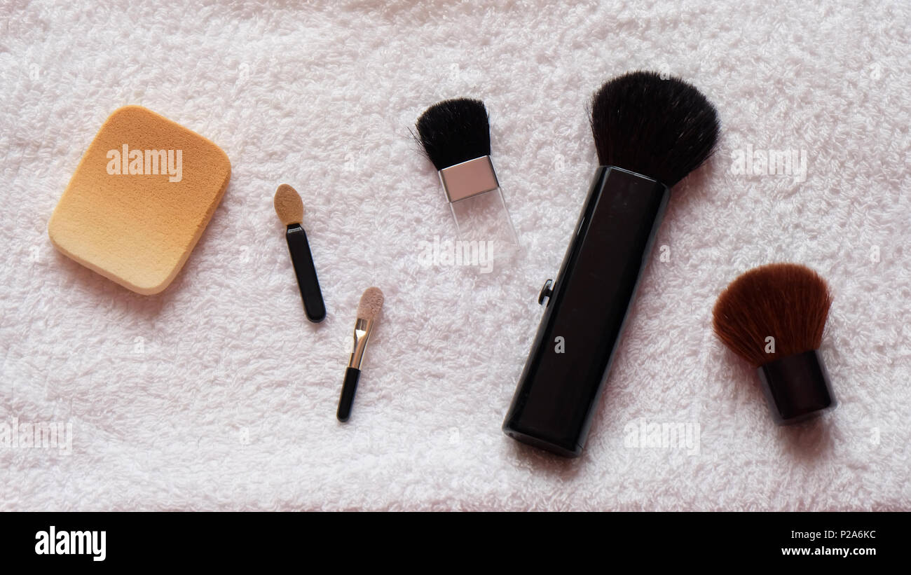 Maquillaje de esponja y pinceles organizados sobre una toalla blanca Foto de stock