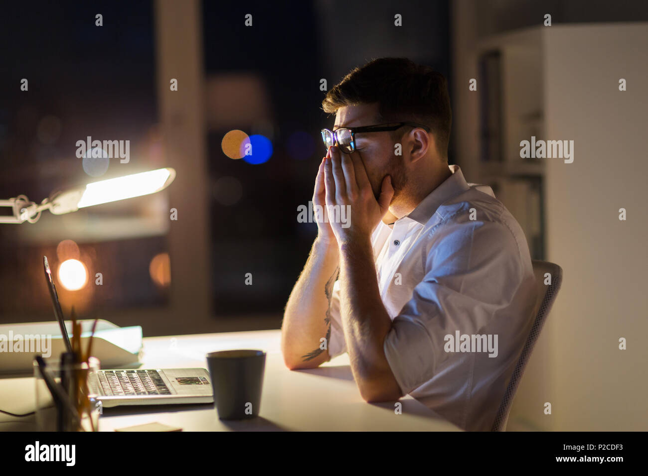 Cansado del empresario con un portátil en la oficina de noche Foto de stock