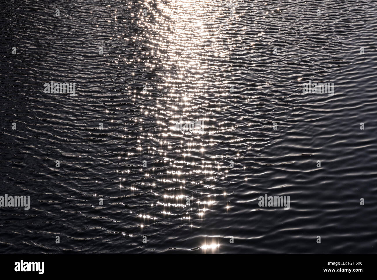 La luz solar centelleantes y reflexionando sobre ondas de agua del canal de negro Foto de stock
