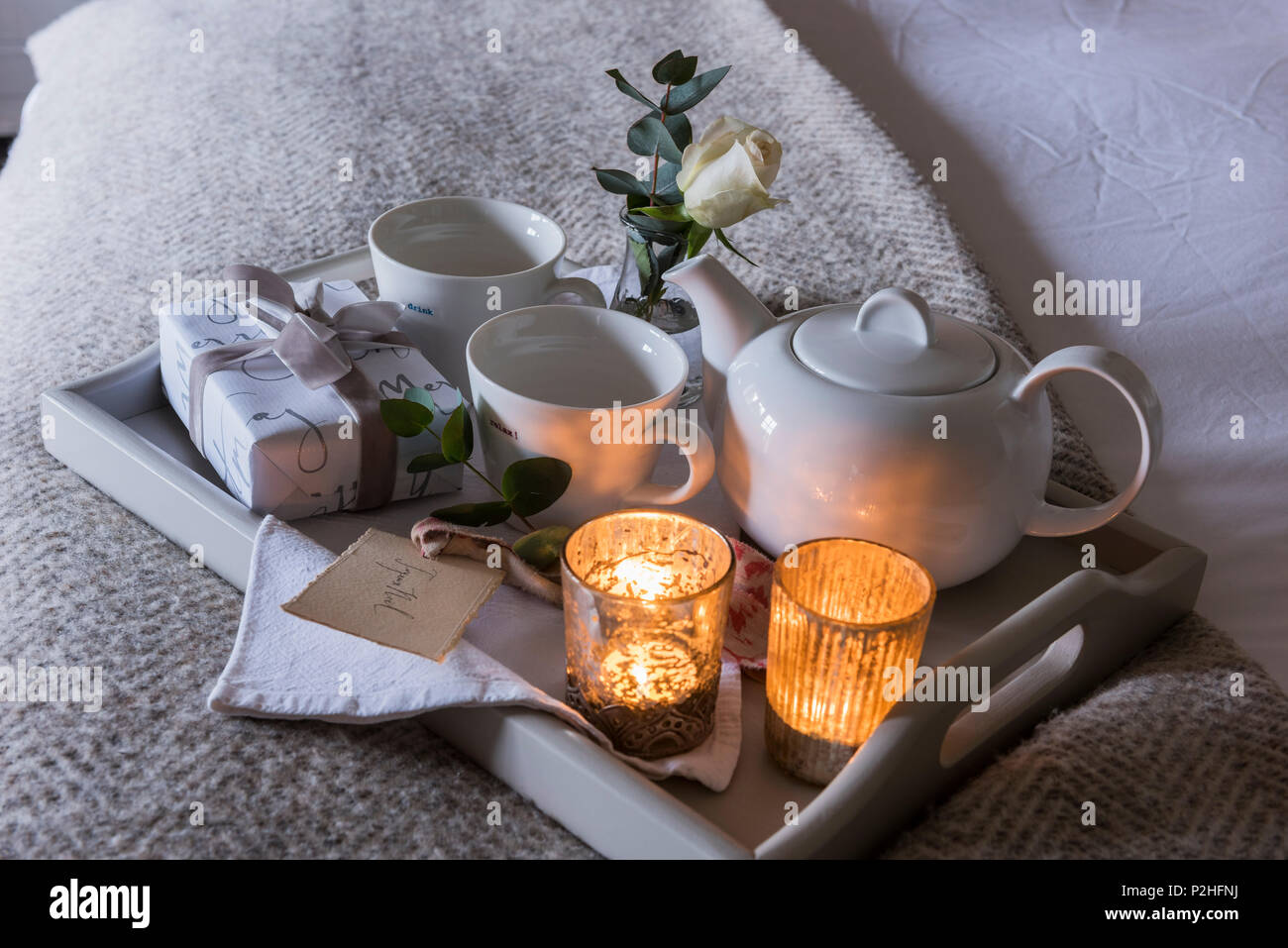 Detalle de una candelita encendida bandeja de desayuno con pequeños envuelto presente y la rosa blanca. Foto de stock
