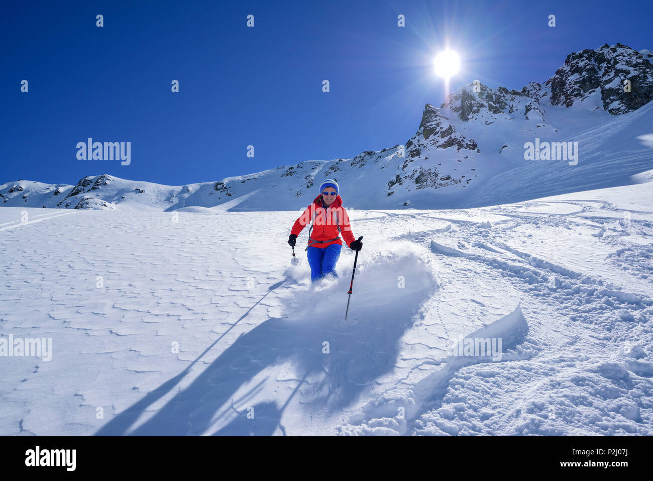 Mujer de regreso de esquí cuesta abajo a través de la nieve polvo de Passo Croce, Passo Croce, Valle Maira, Cottian Alpes, Piamonte, Italia Foto de stock