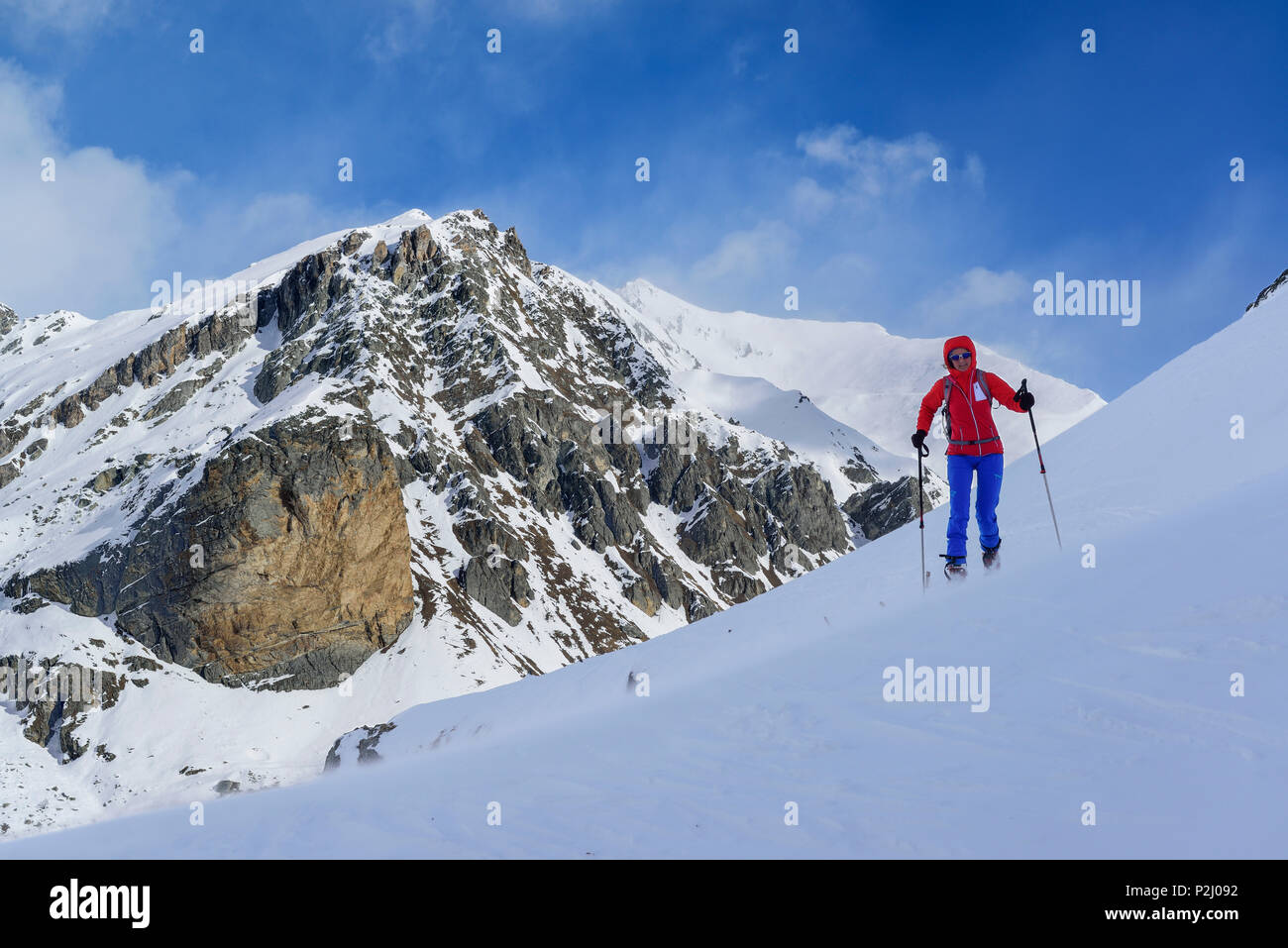 Mujer de regreso de esquí ascendiendo hacia el Monte Faraut, Rocca Senghi y Monte Ferro en antecedentes, Monte, Valle Varait Faraut Foto de stock