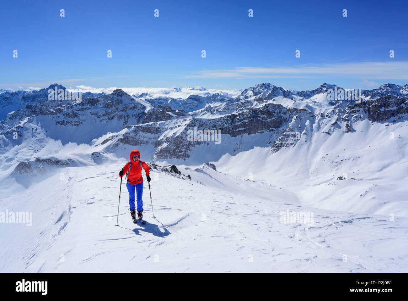 Mujer de regreso de esquí ascendiendo hacia el Monte Faraut, en antecedentes Tete de Moise, Monte, Monte Sautron Cervet y Rocca Bla Foto de stock