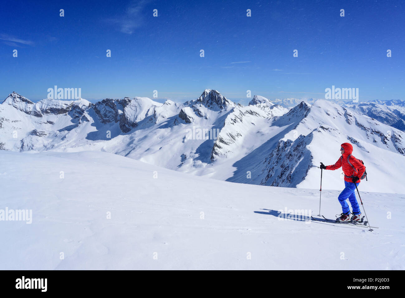 Mujer de regreso de esquí ascendiendo hacia el Monte Faraut, en el fondo Pelvo d'Elva, Monte Camoscere Rocca y la Marchisa, Foto de stock