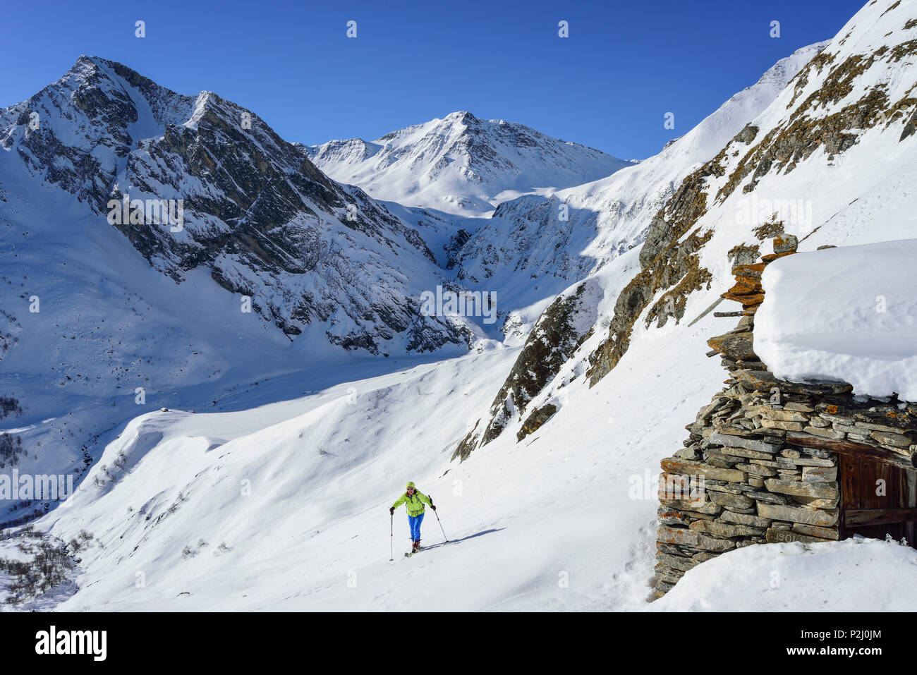 Mujer de regreso de esquí ascendiendo hacia el Monte Salza, en el fondo el monte Pence y Buc Faraut, Monte Salza, Valle Varait Foto de stock