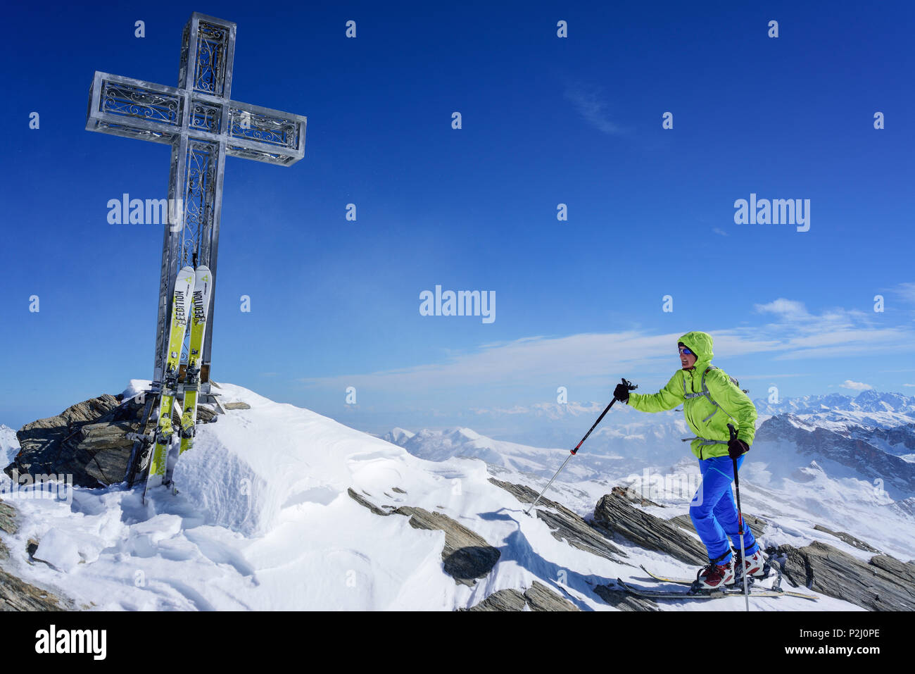 Mujer de regreso de esquí ascendente hacia la cruz en la cima del Monte, el Monte Salza Salza, Valle Varaita, Cottian Alpes, Piamonte, Foto de stock