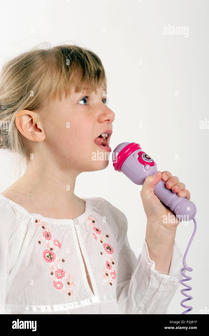 Niña cantando en un micrófono de juguete Fotografía de stock - Alamy