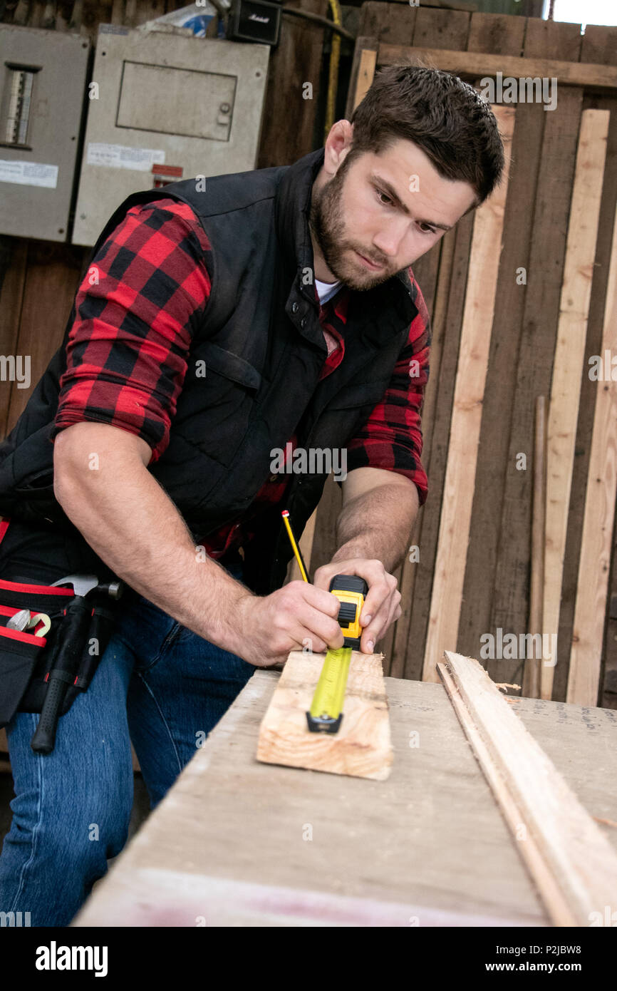 Guapo Carpintero, hombre trabajador de madera medidas y brocas de madera La  madera en el taller de small business Fotografía de stock - Alamy