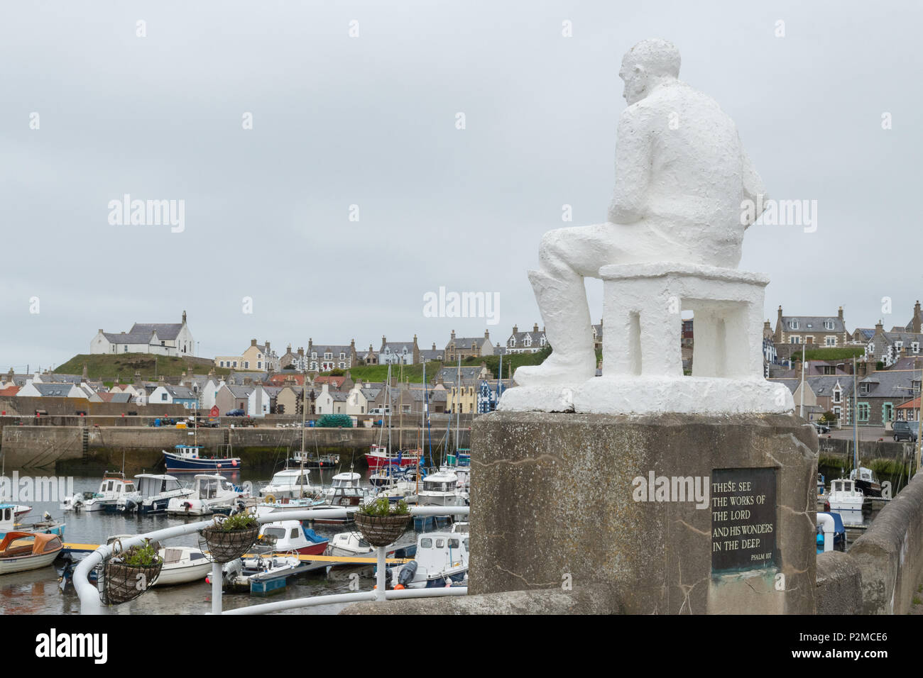 Puerto Fnidochty, Moray, Escocia, Reino Unido - daba por parte de los blancos Mannie - una estatua de un pescador sentado creada en 1959 por el artista local Correna Cowie Foto de stock
