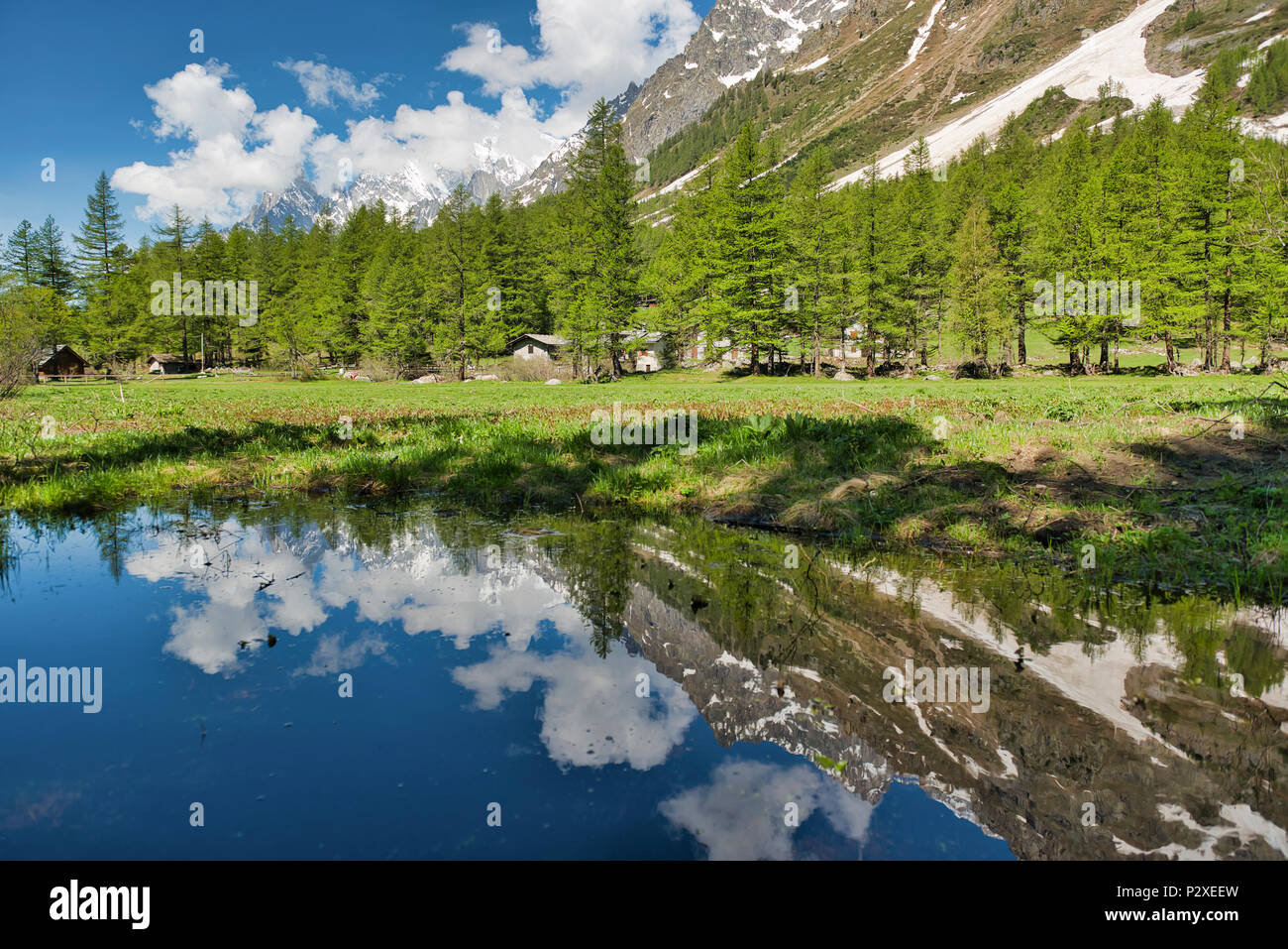 Pequeño lago en Val Ferret con árboles de montañas y nubes reflejadas en el agua de la temporada de primavera Foto de stock