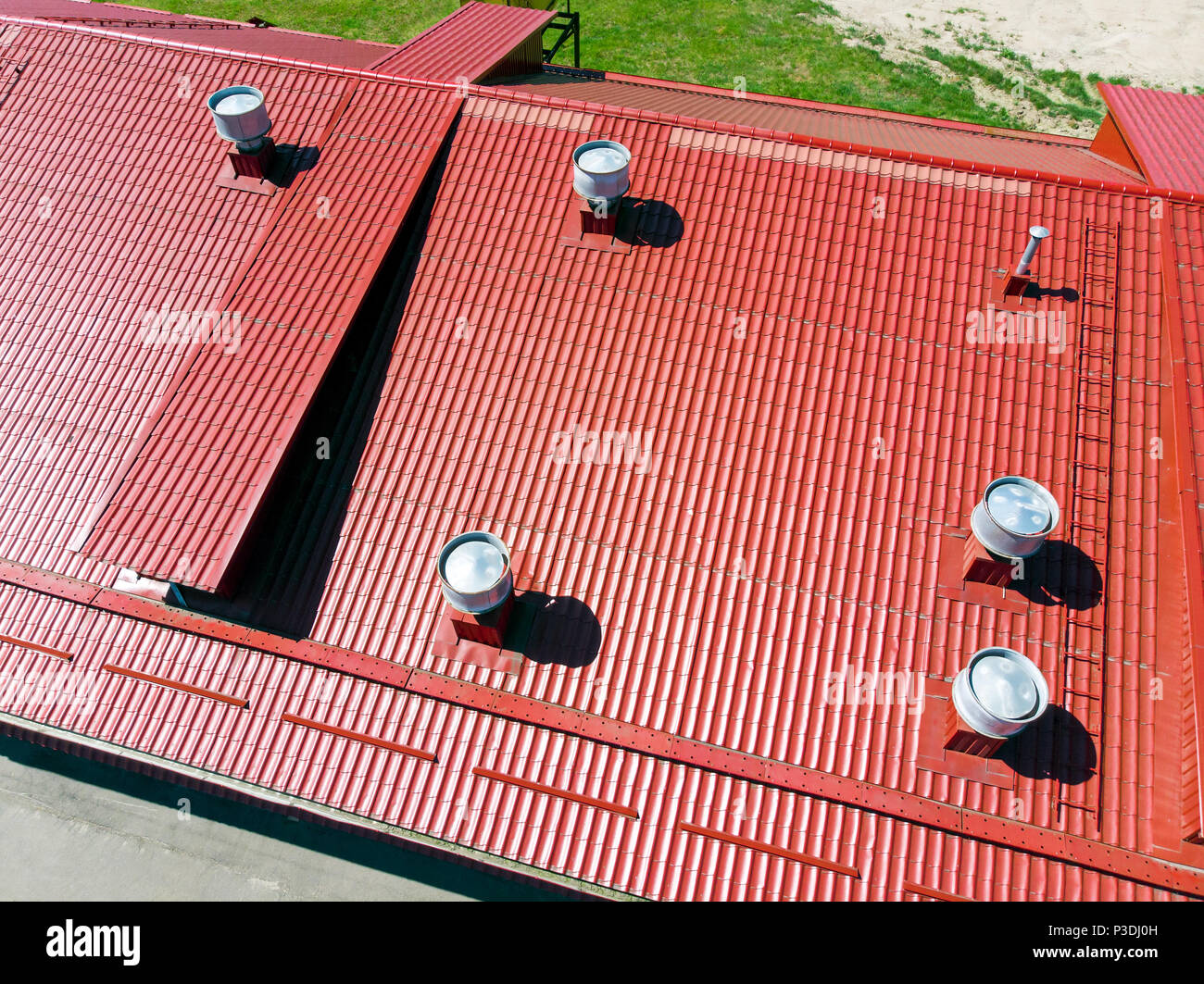 Nuevo almacén de metal rojo con techo instalado tuberías de fotografía aérea de sistemas de ventilación. Foto de stock