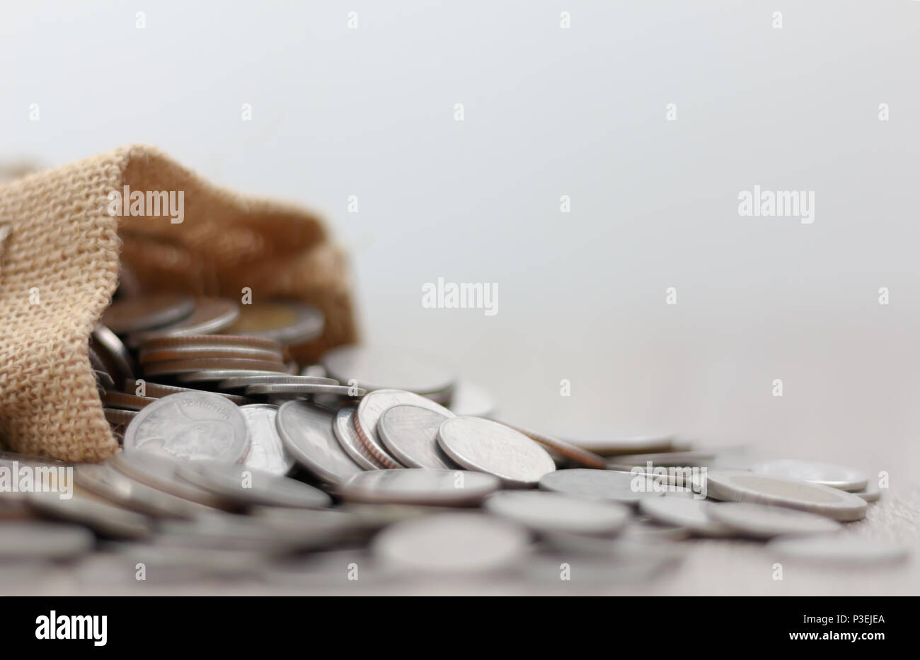 Monedas en el saco sobre la mesa de madera con espacio de copia. Seleccione focus gran profundidad de campo y el fondo borroso. Foto de stock