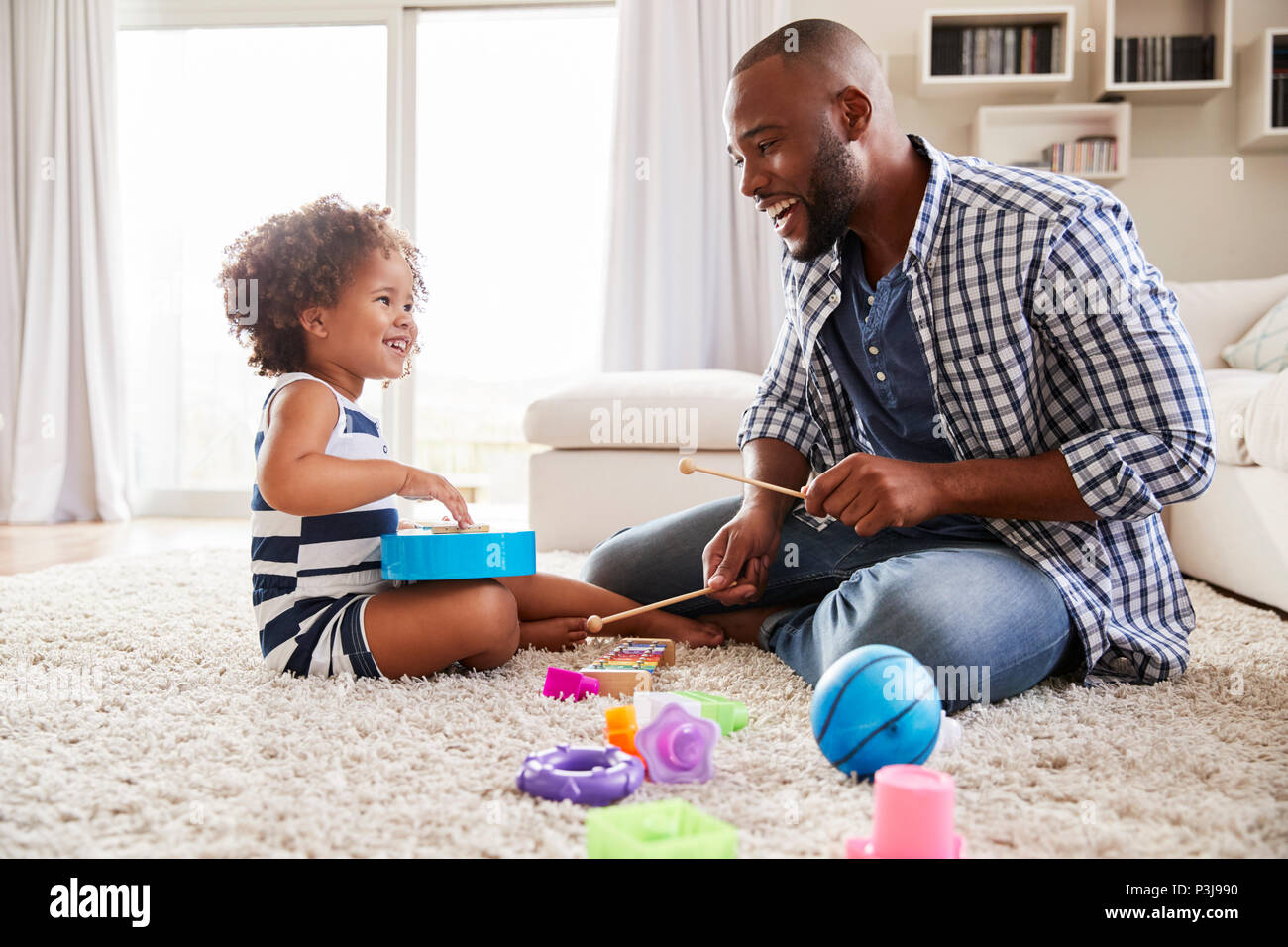 Joven negro padre jugando con su hija en el salón Foto de stock