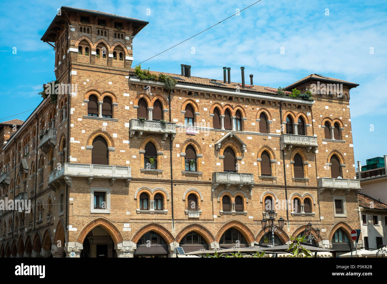 Un viejo y enorme edificio en el centro de la ciudad de Treviso se encuentra en una plaza. Tiene muchos arcos y ventanas. Foto de stock