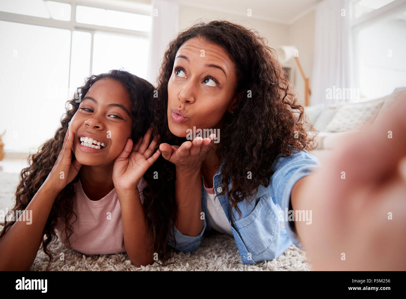 Madre e hija acostado sobre una alfombra y posar para Selfie en casa Foto de stock