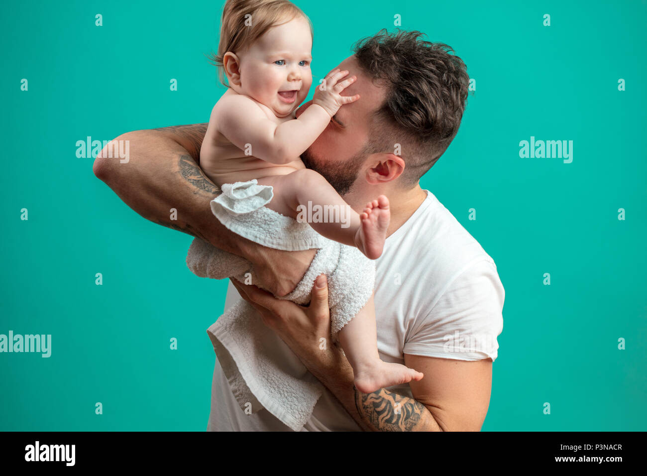Juguetón padre llevar a su niño sonriente en cuello sobre fondo azul. Foto de stock