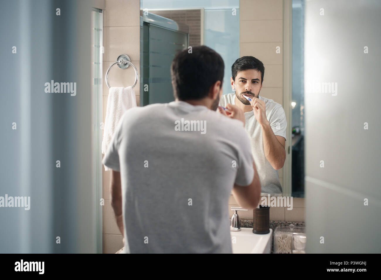 Hombre hispano de cepillarse los dientes en el baño por la mañana Foto de stock