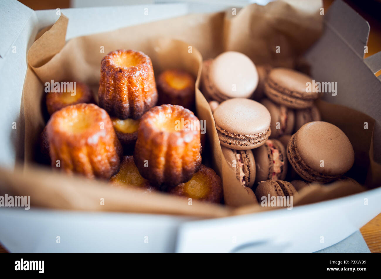 Canneles de Bordeaux con chocolate macarons juntos en caja de regalo Foto de stock