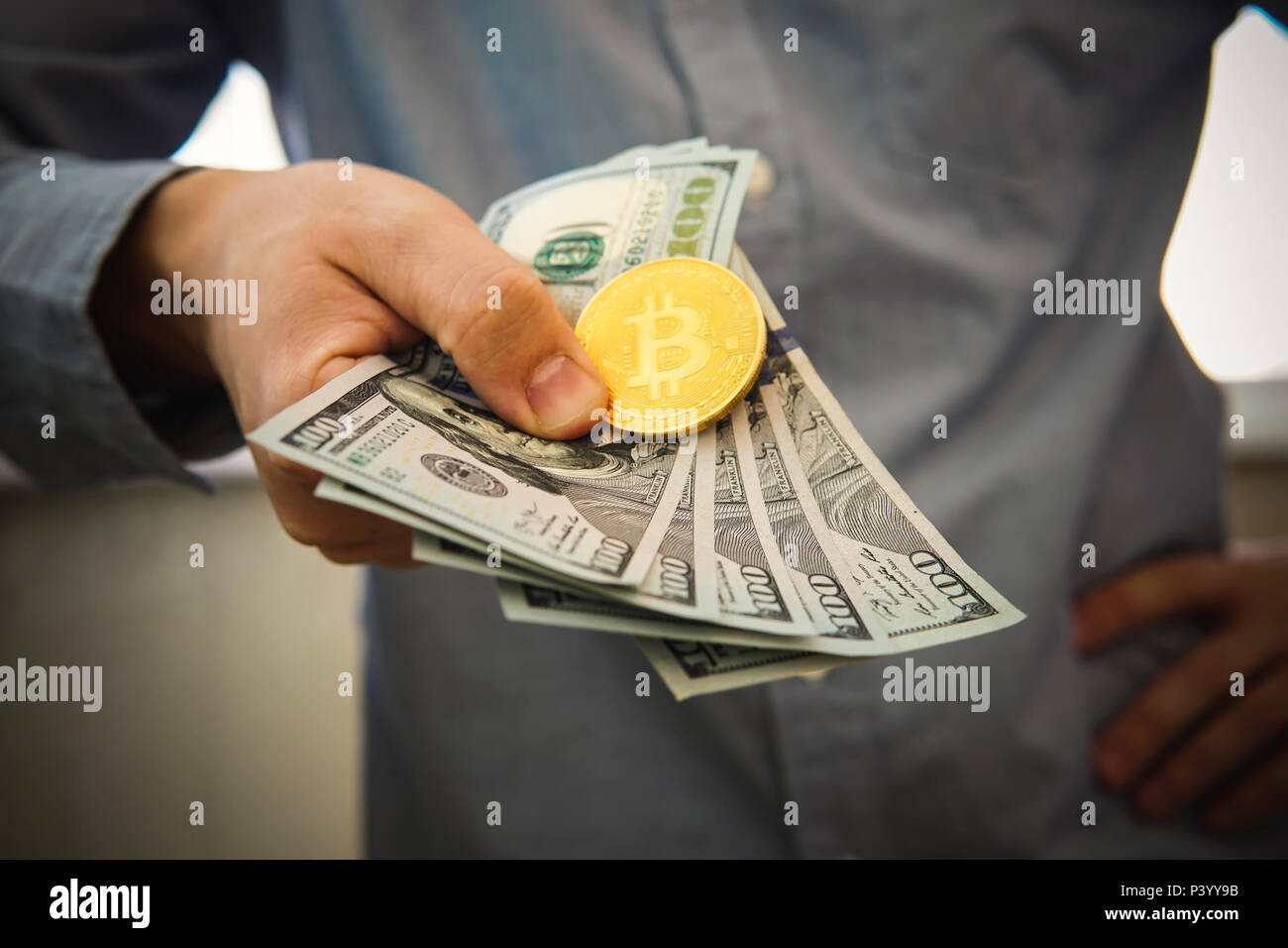 Oro moneda Bitcoin 500 dólares en la mano del hombre en el fondo borroso. Empresario, comerciante de inicio muestra sus ganancias en la tasa de crecimiento de bitcoin Foto de stock