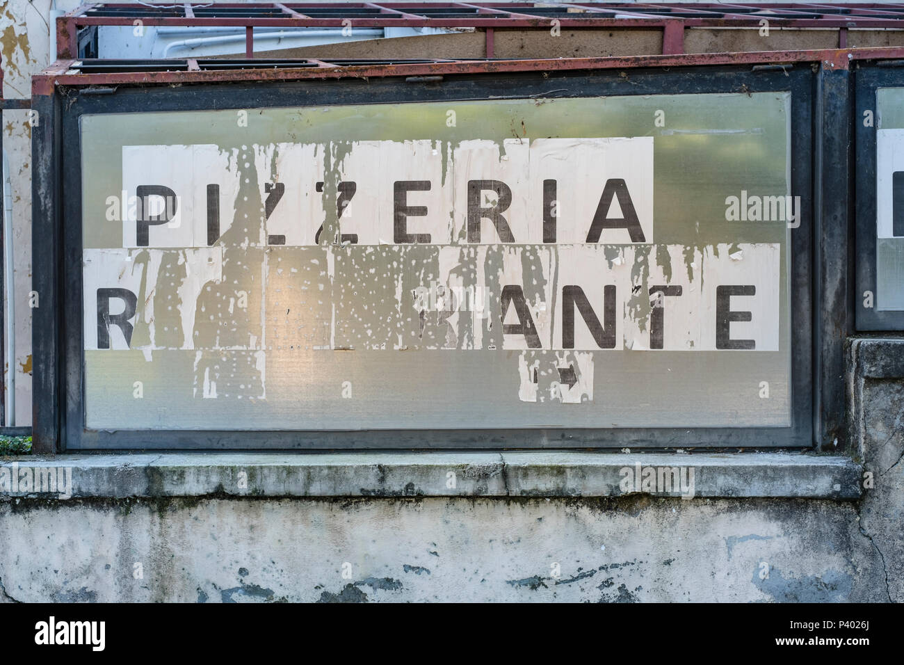 Rundown y capeado pizzería y restaurante italiano firmar en una vieja pared Foto de stock