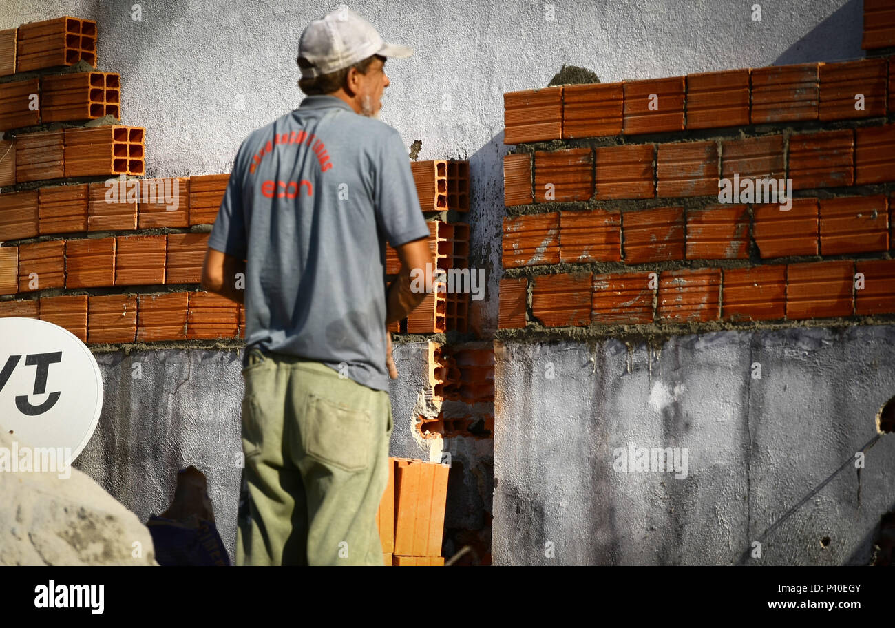 Em construção Pedreiros levantando parede de tijolos. Foto de stock