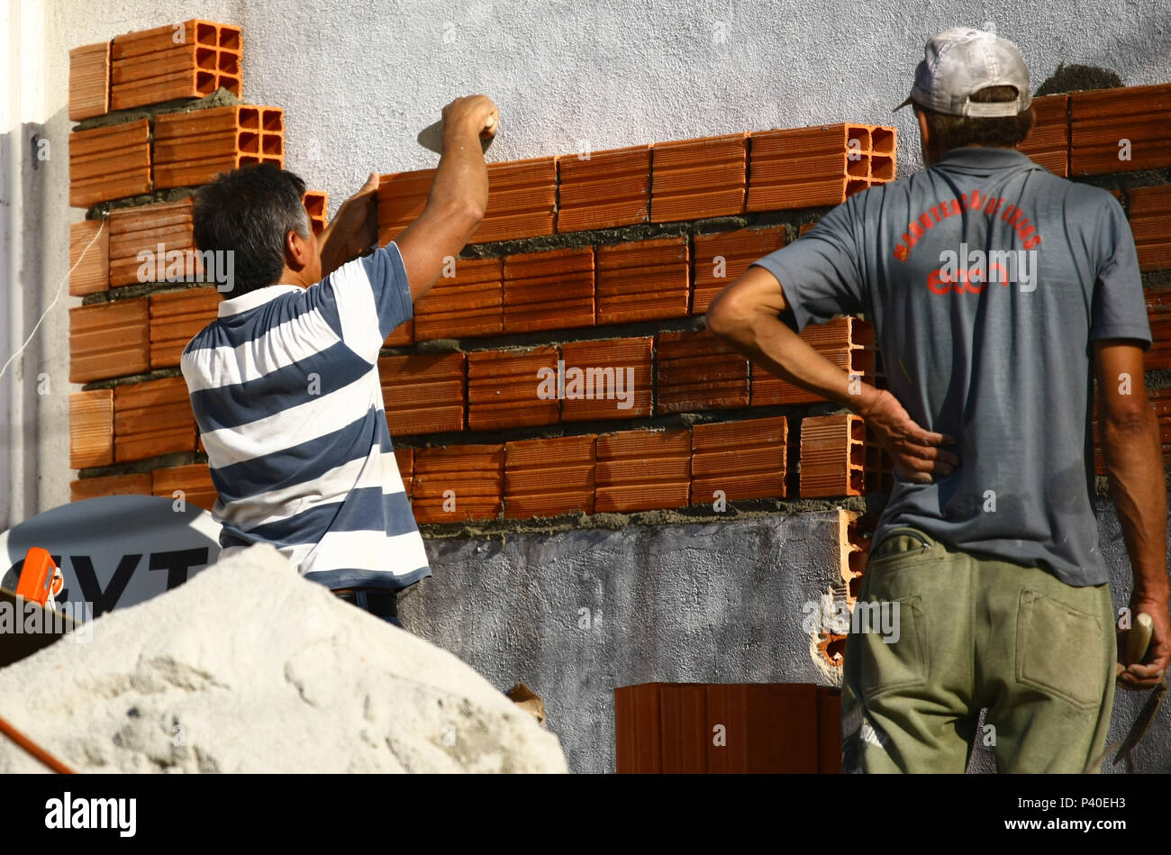 Em construção Pedreiros levantando parede de tijolos. Foto de stock