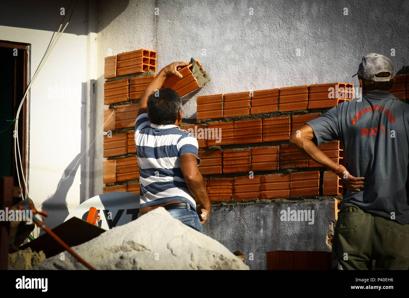 Em construção Pedreiros levantando parede de tijolos. Foto de stock