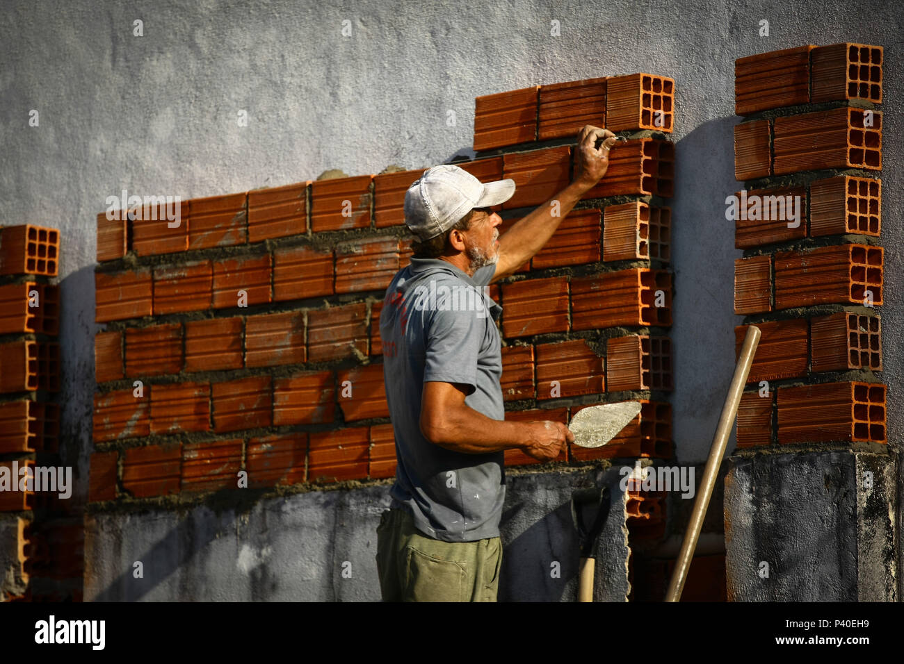 Em construção Pedreiros levantando parede de tijolos. Foto de stock