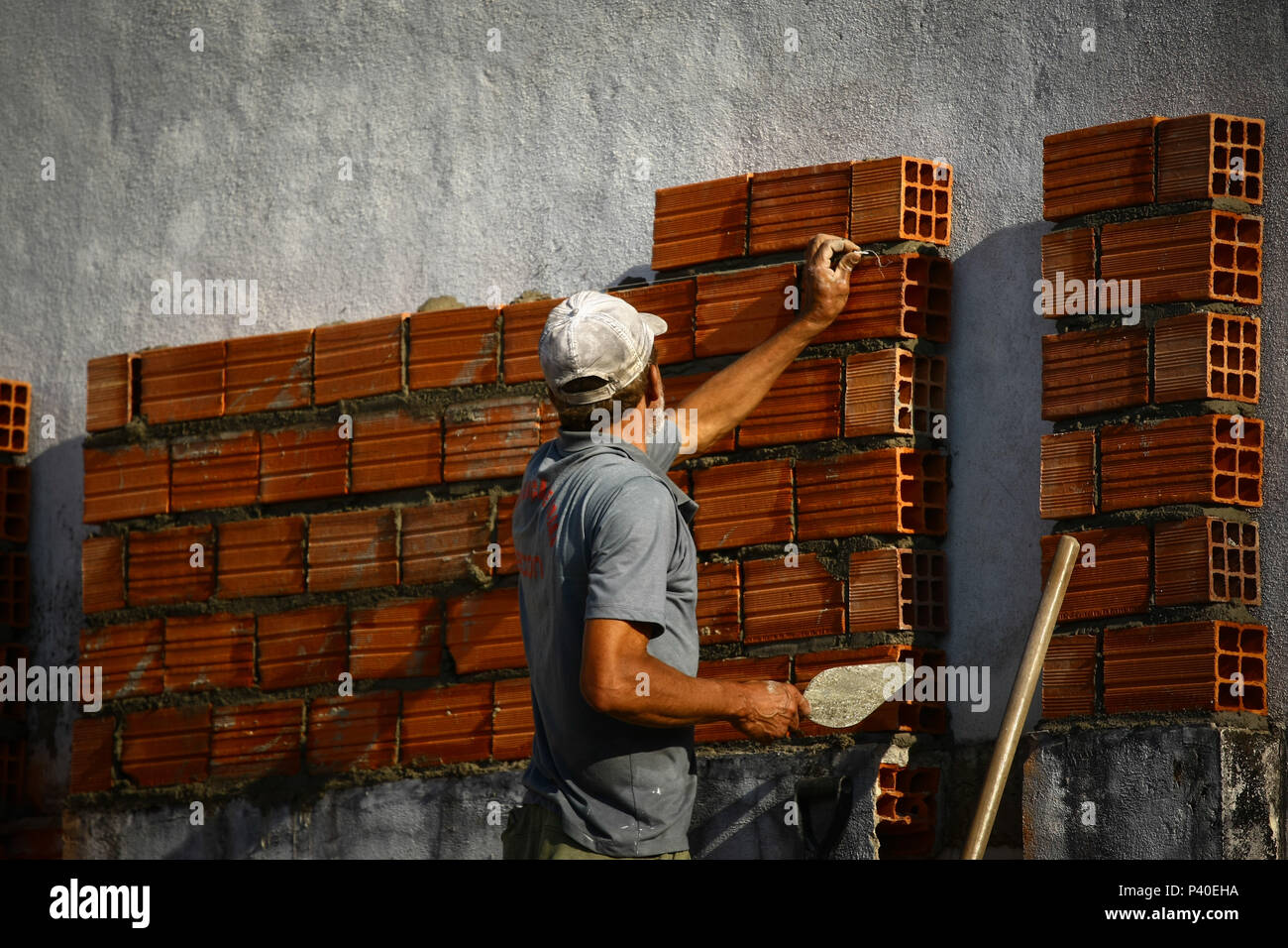 Em construção Pedreiros levantando parede de tijolos. Foto de stock