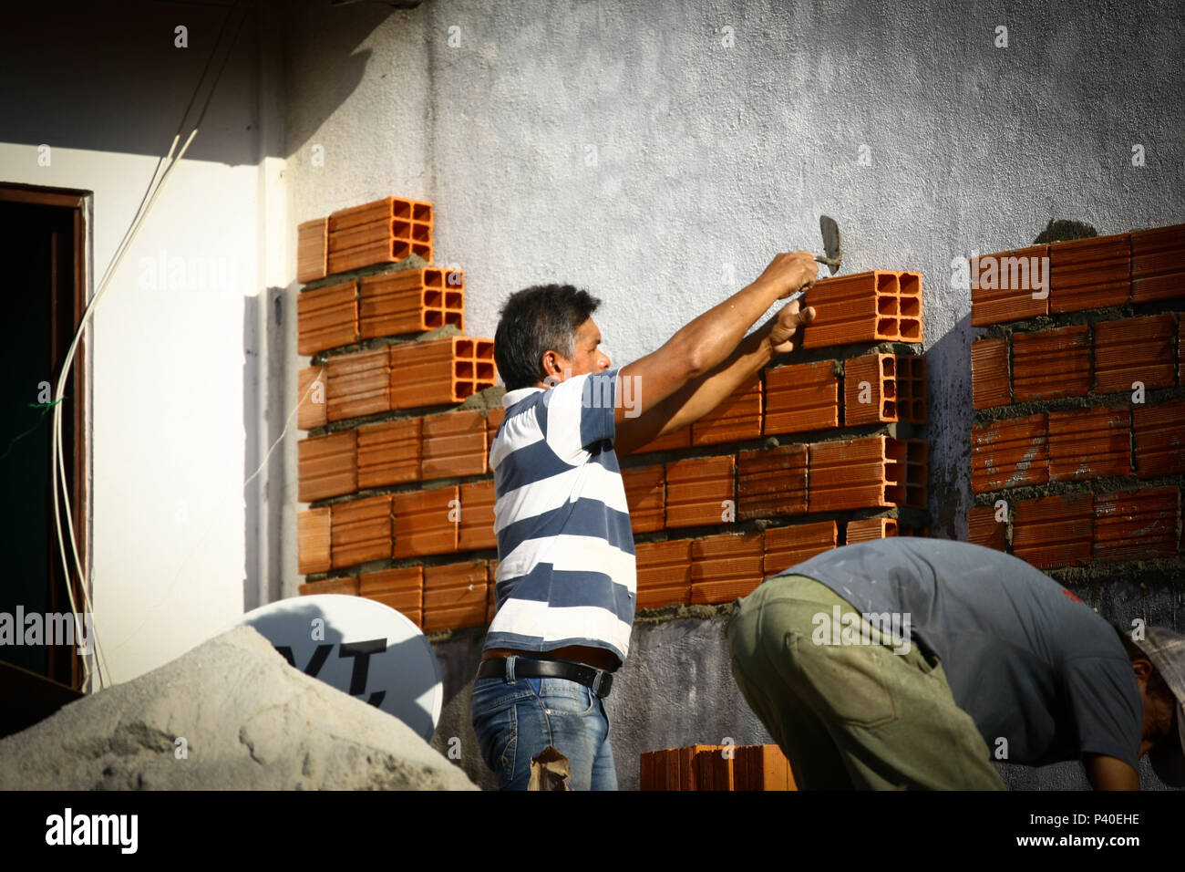 Em construção Pedreiros levantando parede de tijolos. Foto de stock